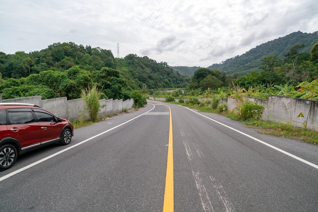 Novo carro Suv vermelho em estrada de asfalto com floresta de montanha verde