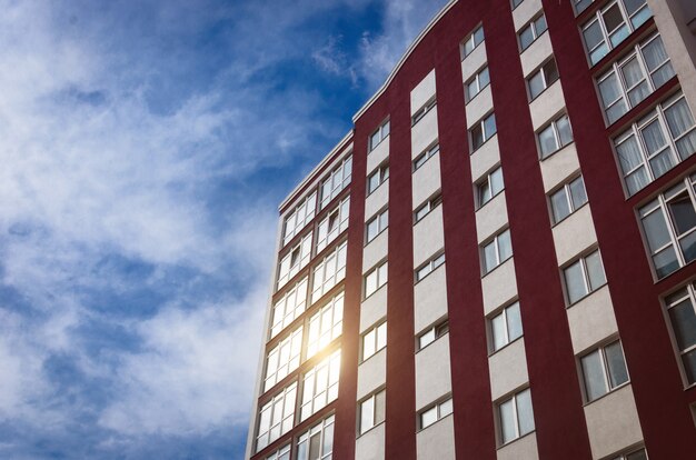 Novo edifício de vários andares contra o céu cujas janelas refletem o sol