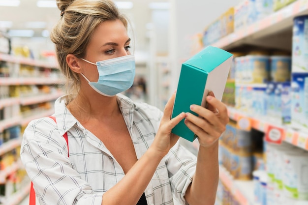 Novo normal nas compras. Mulher jovem com máscara de prevenção em um supermercado durante a pandemia do vírus.