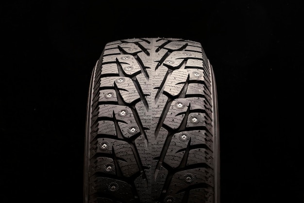 Novo pneu cravejado de inverno em um fundo preto
