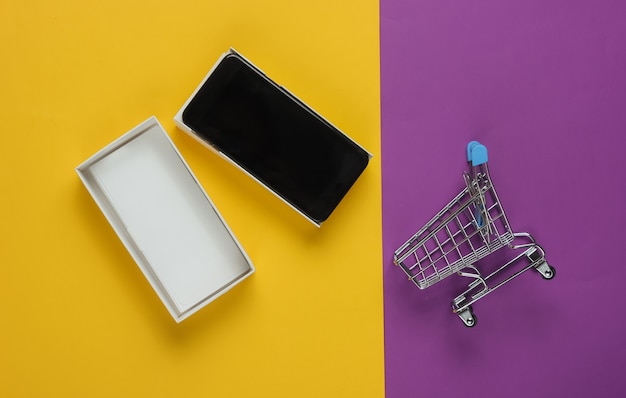 Novo smartphone moderno em caixa e mini carrinho de compras colorido