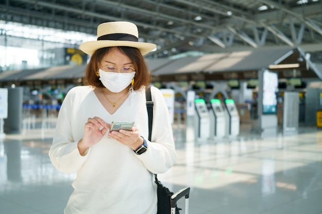 Novo turista normal usando máscara facial está viajando no aeroporto