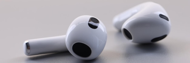 Novos fones de ouvido sem fio brancos em fundo cinza, ouça música, conecte-se em qualquer lugar