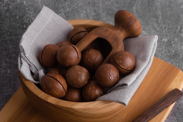 Foto noz de macadâmia orgânica em tigela de madeira e colher. superalimento e conceito de comida saudável.