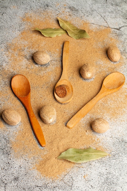 Noz-moscada e noz-moscada em pó e colher de madeira em um balcão de cozinha de mármore cinza