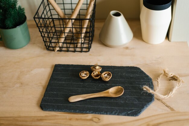 Nozes em uma tábua de cortar ardósia preta e uma colher de pau na bancada da cozinha Escandinava