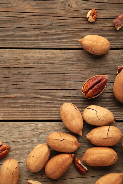 Nozes pecan em uma mesa de madeira marrom. Foto vertical.