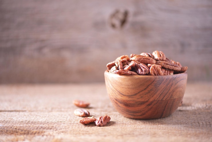 Foto nozes pecan em uma tigela de madeira sobre fundo texturizado de madeira copie o espaço conceito de comida vegetariana vegana superalimento macro de foco seletivo de nozes pecan lanche saudável