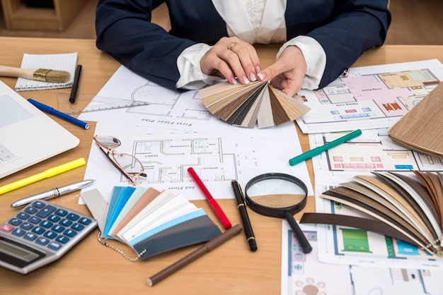 Nterior Designer mit Farbmuster und Bauplänen im Büro