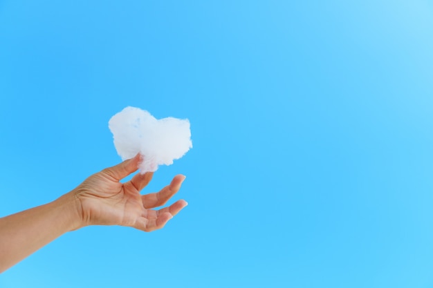 Nube blanca en la mano contra el cielo azul.