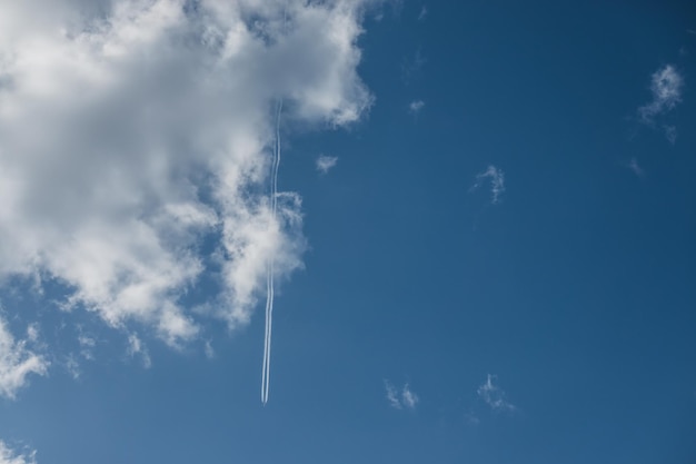 nube blanca y un rastro de avión en el cielo azul