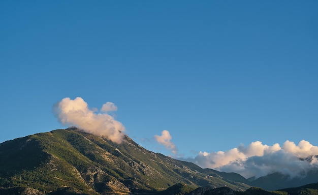 Nube en una cadena montañosa en los rayos del sol al atardecer idea para un paisaje natural de fondo o protector de pantalla de la costa del mar Egeo