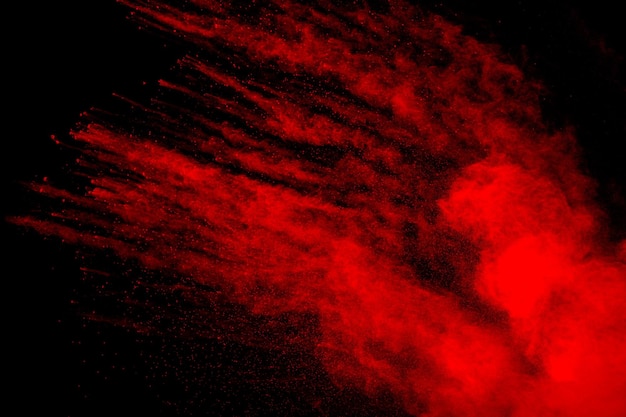 Nube de explosión de polvo rojo sobre fondo negro Movimiento congelado de salpicaduras de partículas de polvo de color rojo