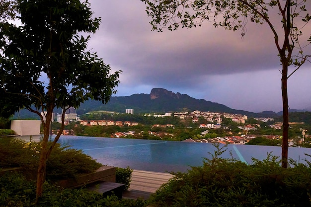 La nube lluviosa de la tarde trae lluvia a la ciudad bajo una colina verde