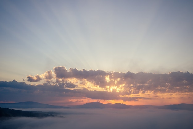 Nubes del amanecer en la cima de la montaña rocosa con brumoso, niebla picos paisaje al atardecer.