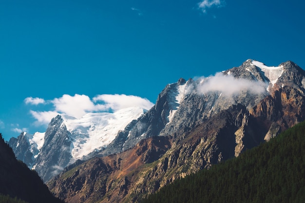 Nubes bajas y niebla en la cima de la cordillera. Glaciar bajo el cielo azul claro.