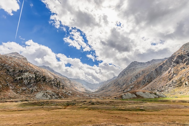 Foto nubes bajas sobre los picos alpinos prado plano hierba amarilla sendero de avión cielo azul valle de aosta italia