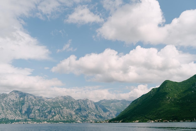 Nubes blancas sobre un cielo azul sobre un fondo de montañas verdes vista desde perast