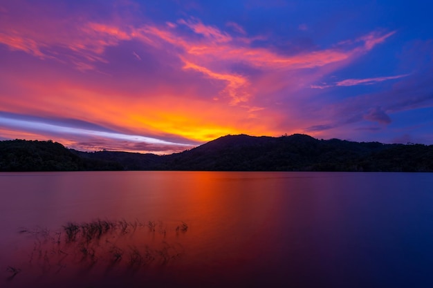 Nubes de cielo al atardecer o al amanecer sobre las montañasHermosa puesta de sol refleja o luz del amanecer en la superficie del aguaPaisaje de naturaleza increíble Fondo de nubes de cielo colorido