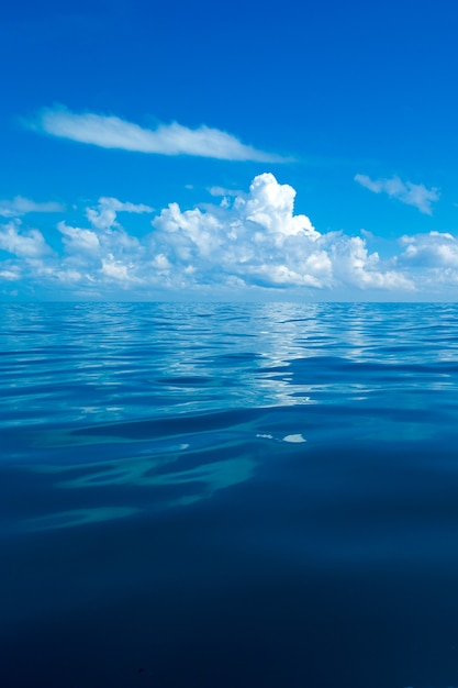 Nubes en el cielo azul sobre el mar en calma con reflejo de la luz del sol