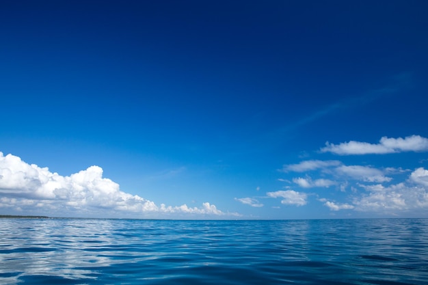 Nubes en el cielo azul sobre el mar en calma con reflejo de la luz del sol