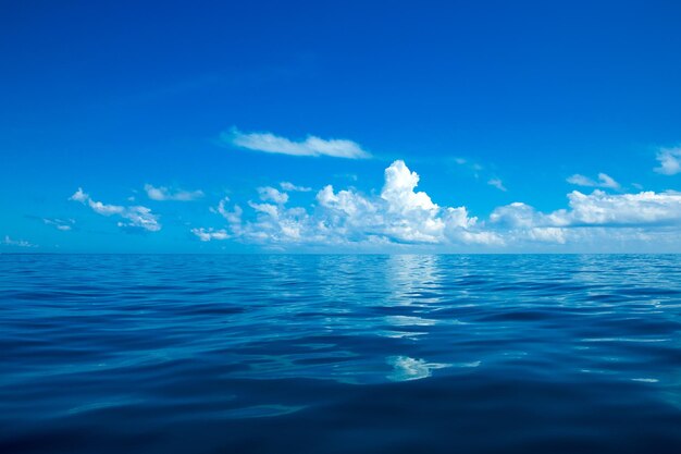 Nubes en el cielo azul sobre el mar en calma con reflejo de la luz del sol