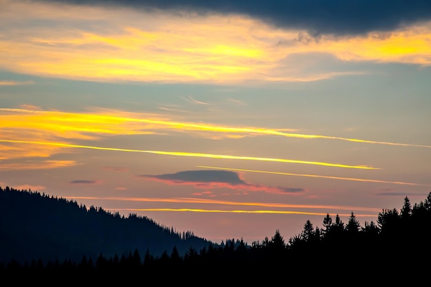 Nubes coloridas en el cielo al atardecer contra el telón de fondo de una zona forestal montañosa