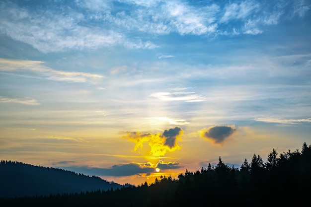 Nubes coloridas en el cielo al atardecer contra el telón de fondo de una zona forestal montañosa