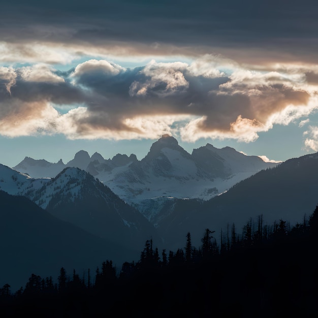 Nubes dramáticas enmarcan picos de montañas y árboles altísimos en silueta para las redes sociales