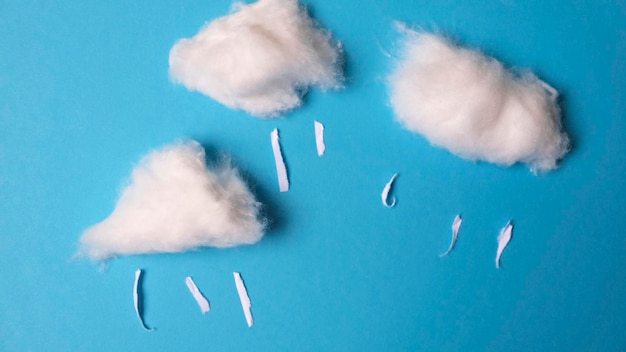 Nubes y lluvia hechas con algodón sobre fondo azul.