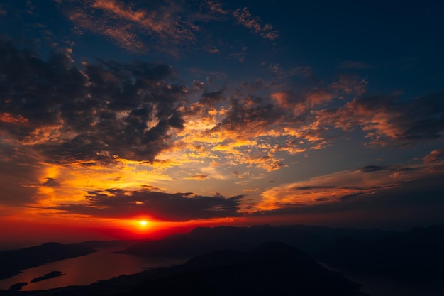 Nubes naranjas en los rayos del sol sobre la vista de la bahía desde el monte lovcen