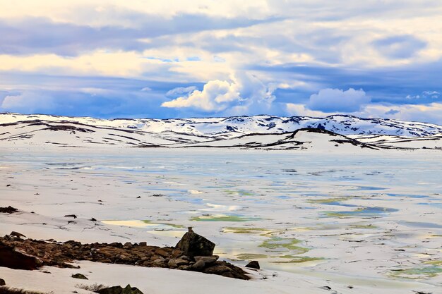 Nubes sobre las montañas cubiertas de nieve helada y el lago