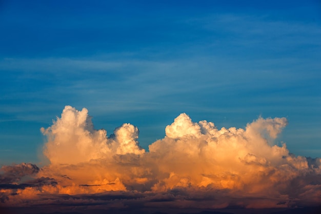 Nubes de tormenta cumulonimbus esponjosas y blancas grandes en un cielo azul profundo al atardecer