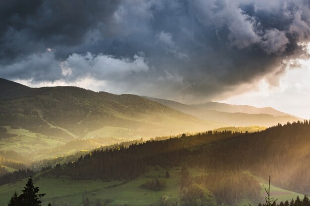 Nubes de tormenta sobre las montañas y el bosque durante la puesta de sol