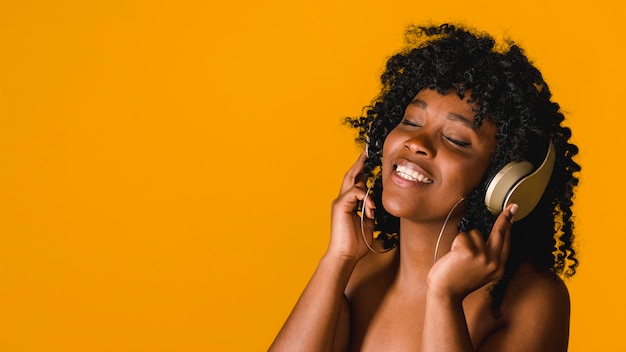 Foto nude jovem mulher afro-americana a apreciar a música em fones de ouvido no estúdio