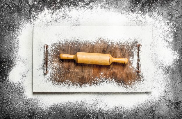Nudelholz für Teig auf Schneidebrett auf rustikalem Tisch.