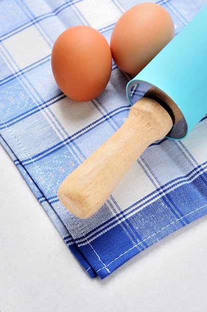 Nudelholz und Eier auf dem Tisch mit einem blauen Tuch