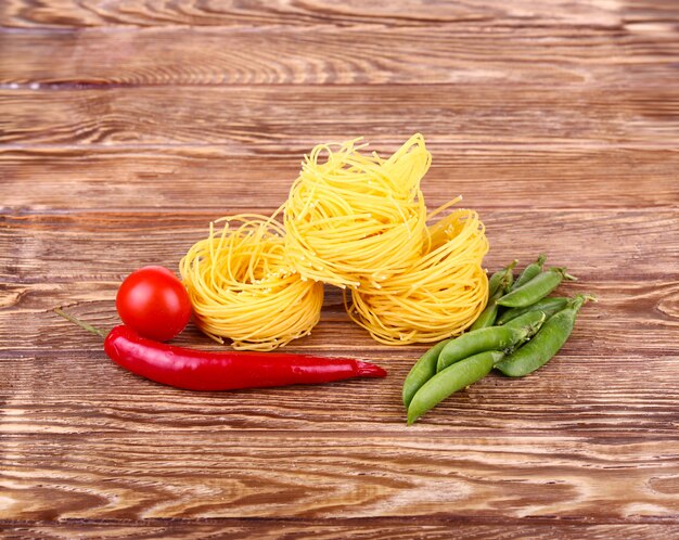 Nudeln an der Holzwand mit Tomaten, Erbsen und Paprika