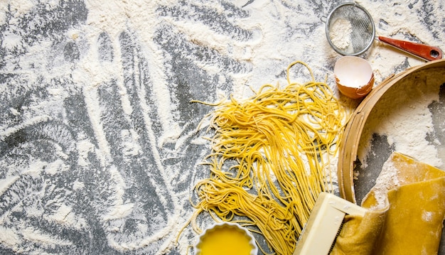 Nudeln kochen Der Nudelhersteller mit Sieb, Eiern und Mehl auf dem Steintisch