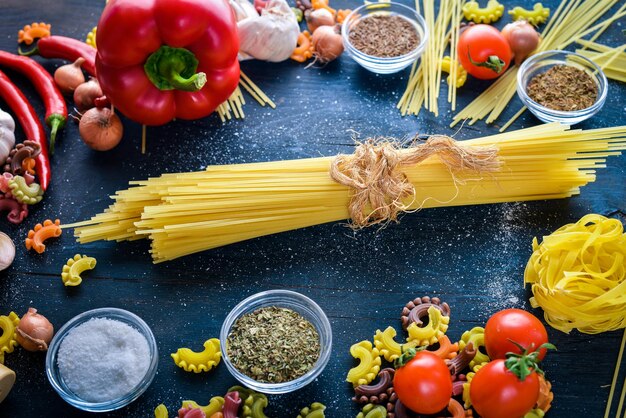 Nudeln mit Gemüse Kirschtomaten Chilischoten und Knoblauch auf einem hölzernen Hintergrund Freier Platz für Text Ansicht von oben