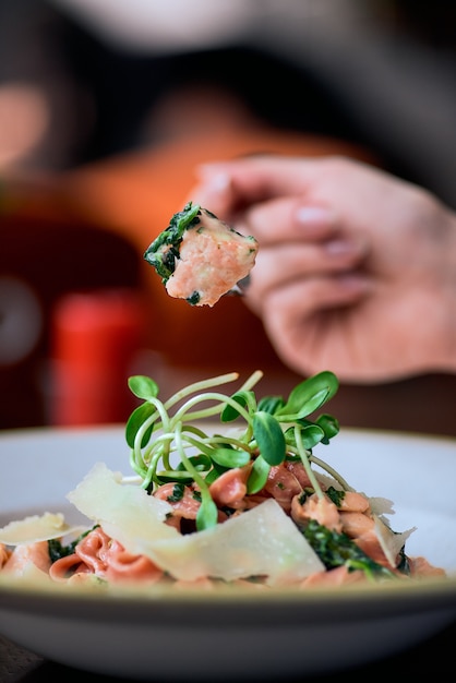 Nudeln mit Lachs und Spinat auf hölzernem Hintergrund