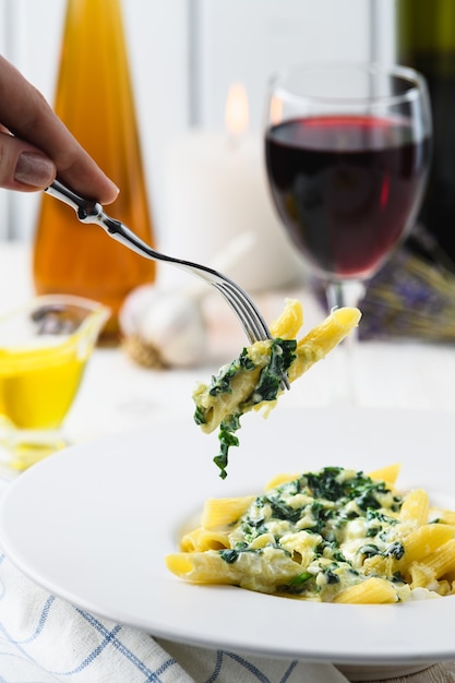 Nudeln mit Mozzarella-Spinat und Wein auf hellem Hintergrund.