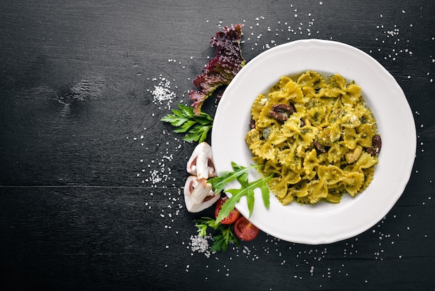 Nudeln mit Spinat, Oliven und Pilzen mit Parmesan-Käse Italienisches Essen auf einer schwarzen Holzoberfläche Freier Platz für Ihren Text Ansicht von oben
