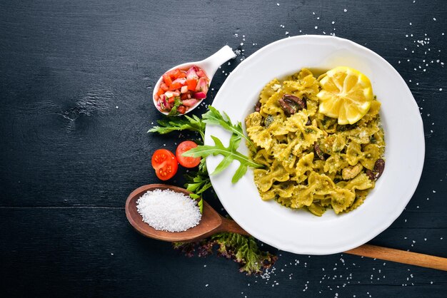 Nudeln mit Spinat, Oliven und Pilzen mit Parmesan-Käse Italienisches Essen auf einer schwarzen Holzoberfläche Freier Platz für Ihren Text Ansicht von oben