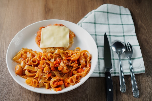 Nudeln mit Tomatensauce, frittiertem, knusprigem Schweinekotelett und einem Blatt Käse