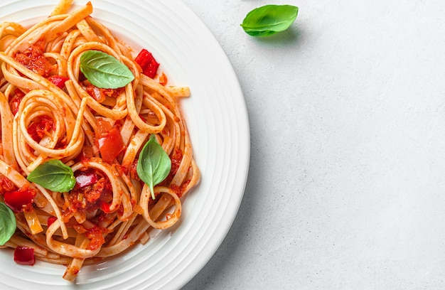 Nudeln mit Tomatensauce und frischem Basilikum auf grauem Hintergrund