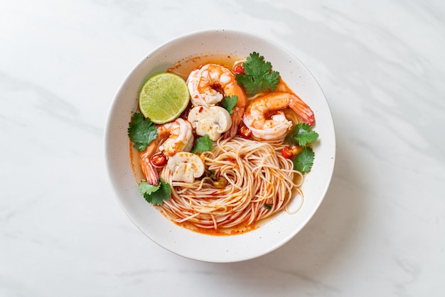 Nudeln mit würziger Suppe und Garnelen in weißer Schüssel (Tom Yum Kung) - asiatische Küche