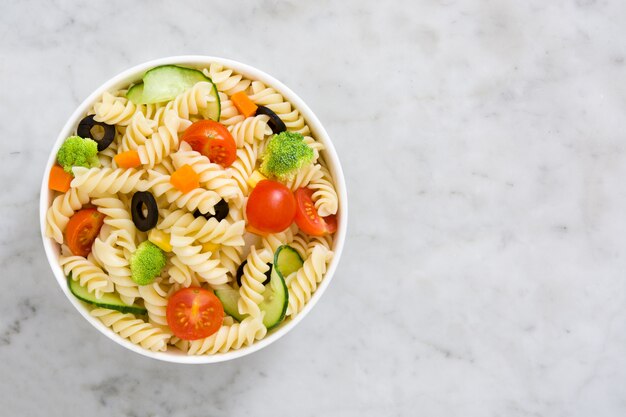 Nudelsalat in einer Schüssel auf Draufsicht des weißen Marmors