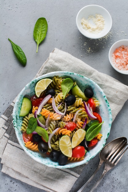 Nudelsalat mit bunten Fusilli und Gemüse in einer Keramikplatte. Draufsicht.