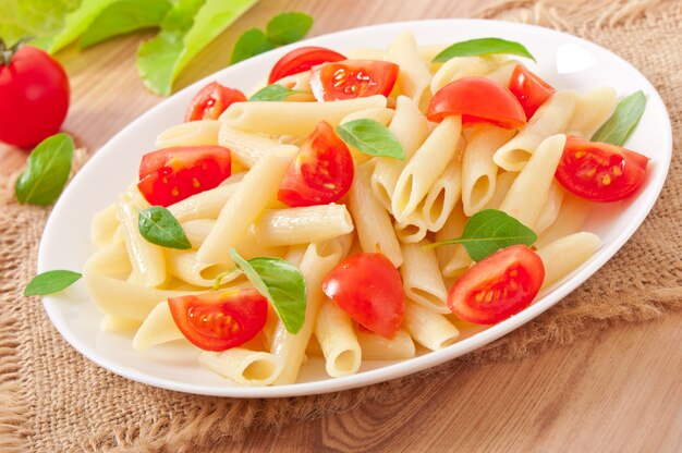 Nudelsalat mit Kirschtomaten und frischen Basilikumblättern